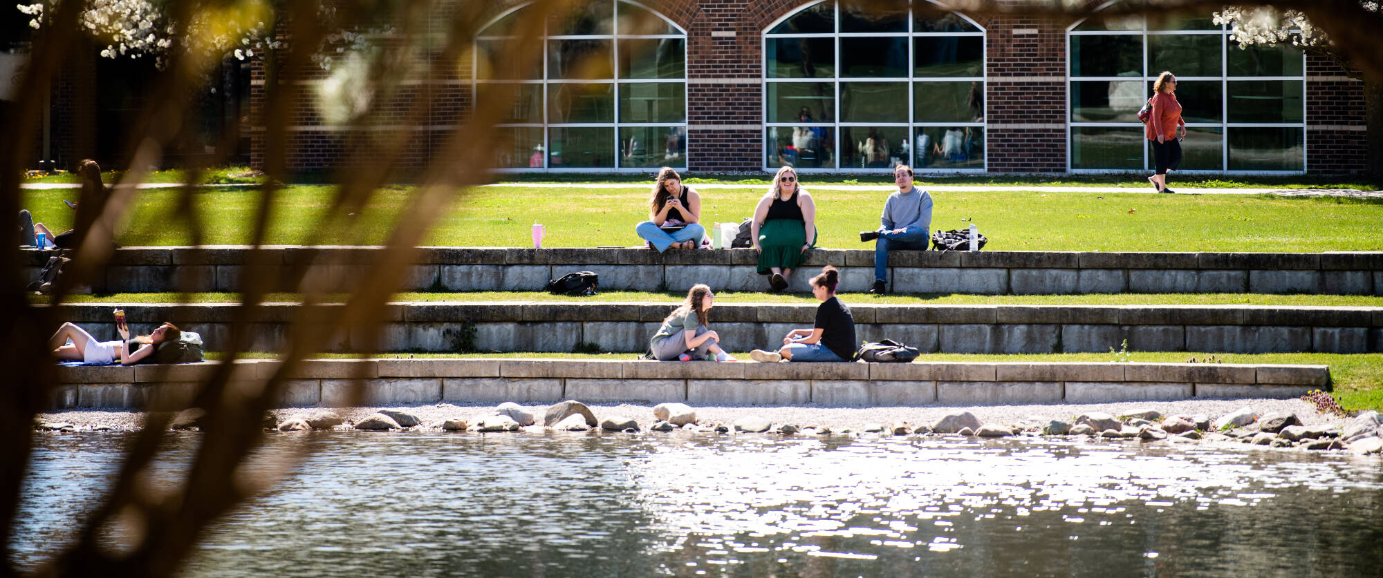 Students sitting by a pond